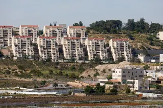 The Kiryat Arba settlement appears in the background near Palestinian houses adjacent to road 60, near Hebron, in the Israeli-occupied West Bank, May 7, 2026. REUTERS/Mussa Qawasma